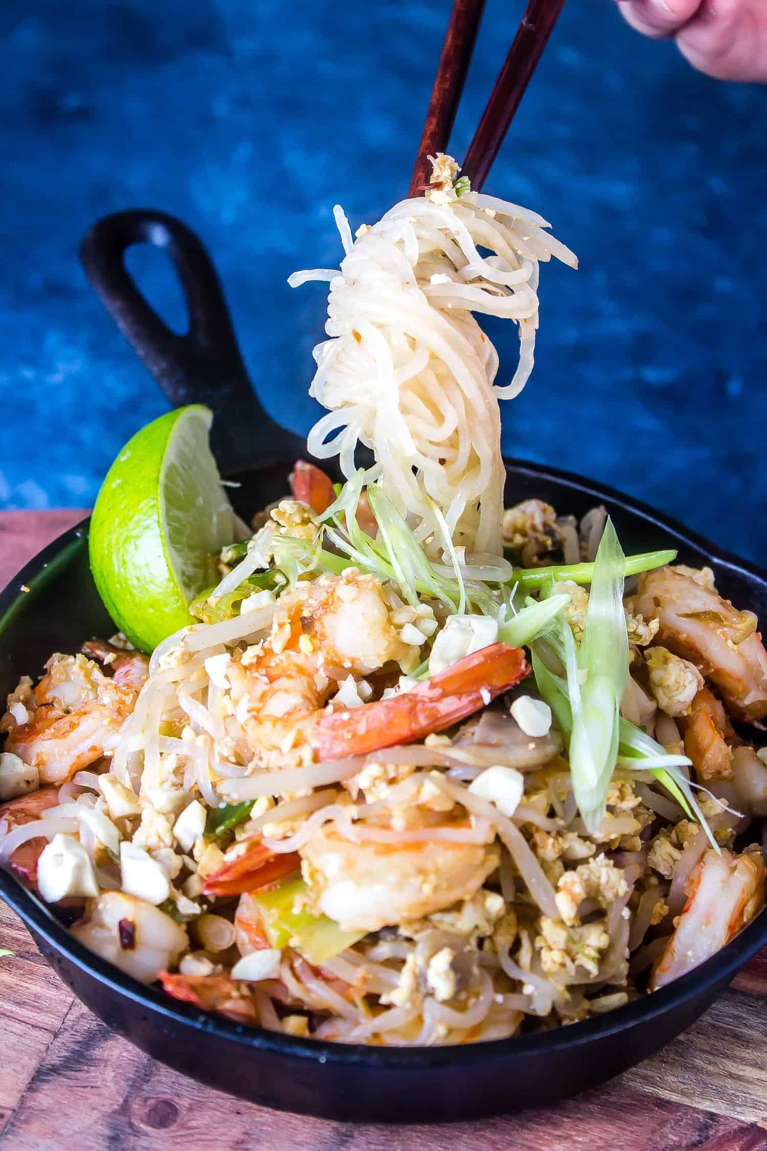 pad thai with noodles being picked up by chopsticks 