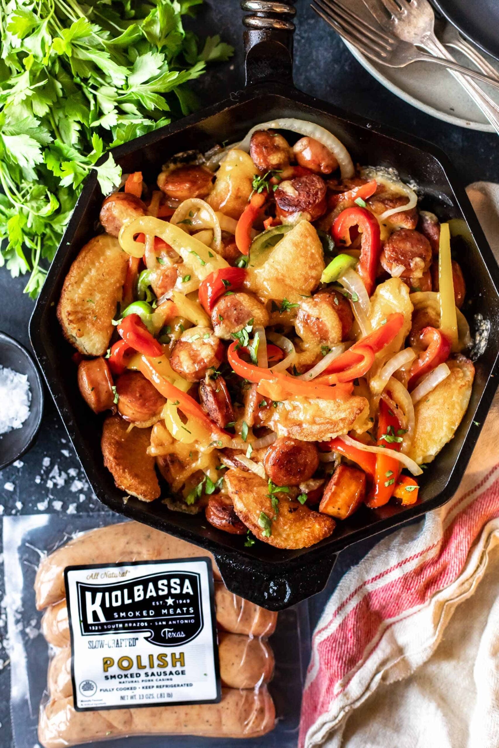 Cast Iron Skillet filled with cooked peppers, onions, rounds of sausage and pierogi