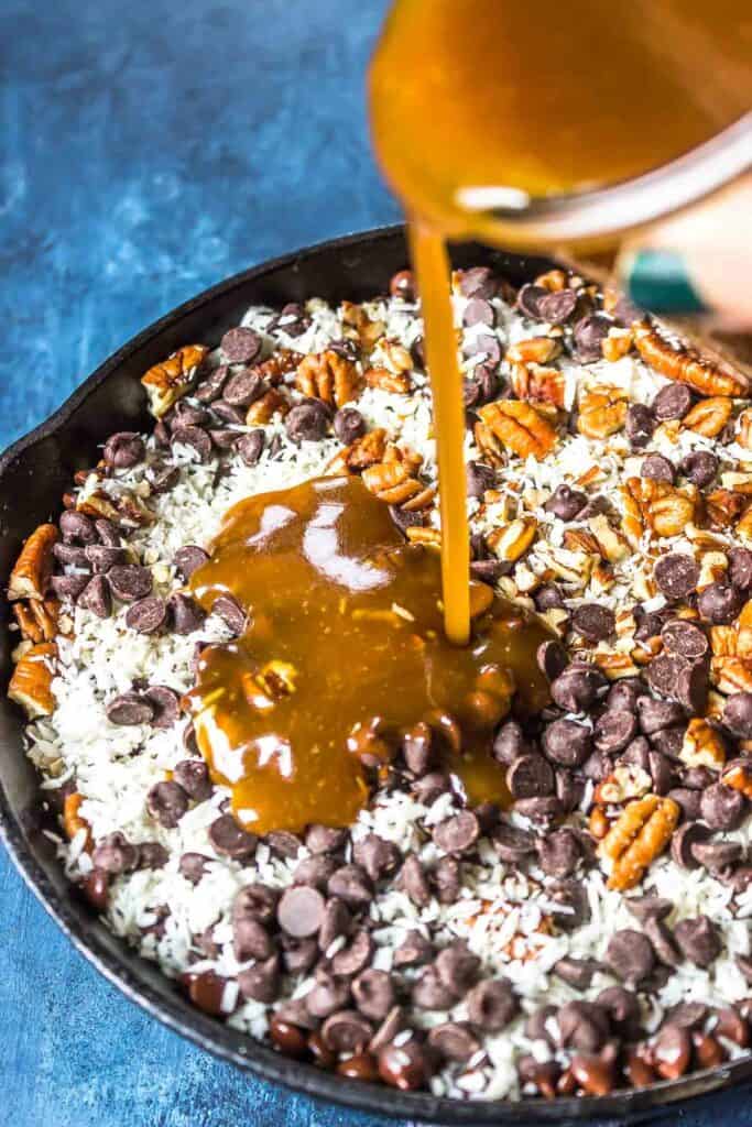 chocolate chips, coconut, pecans, in skillet with caramel being poured over top