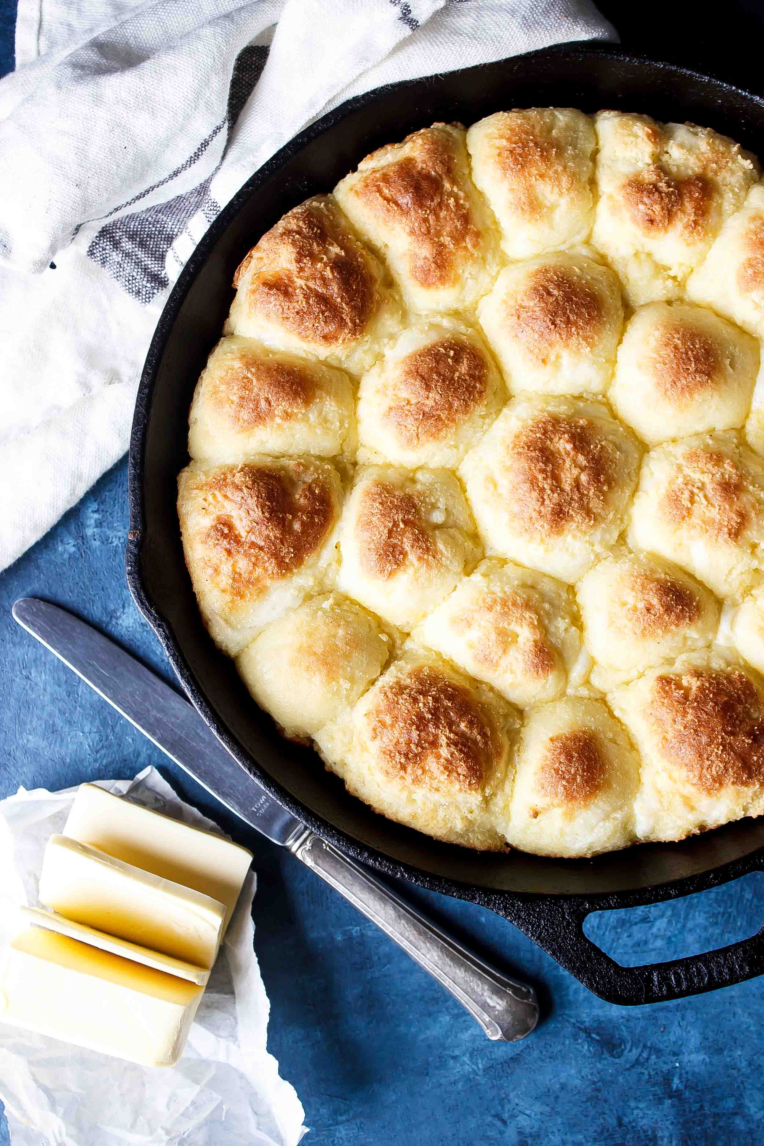 baked rolls in cast iron skillet with knife and butter